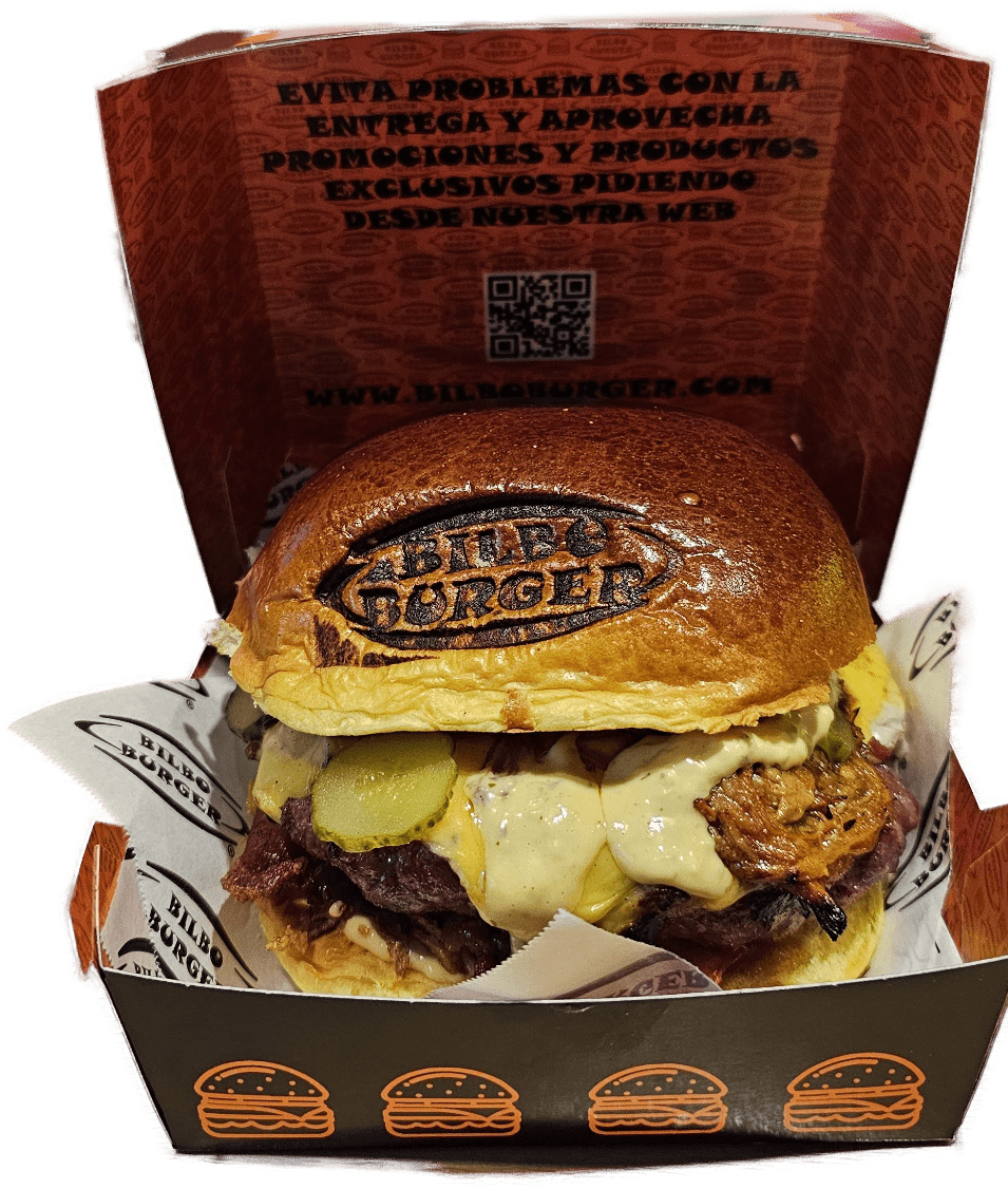 Una suculenta hamburguesa de Bilboburger servida en su icónica caja con el mensaje promocional en el interior, mostrando un QR y la dirección web de la marca.